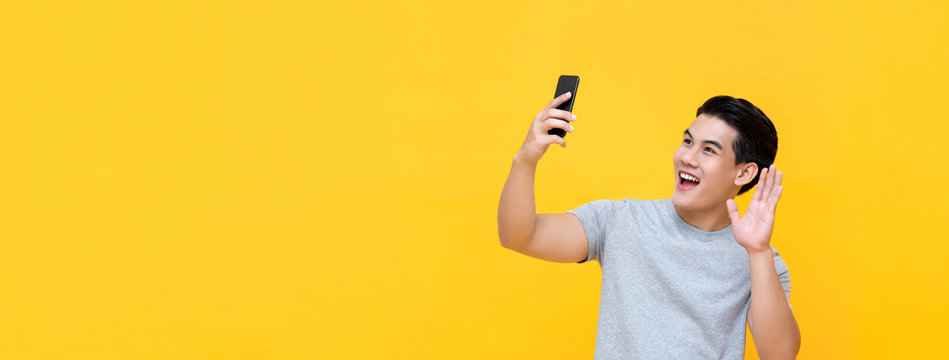 Smiling Asian Man Waving Hand While Making Video Call On Smartphone