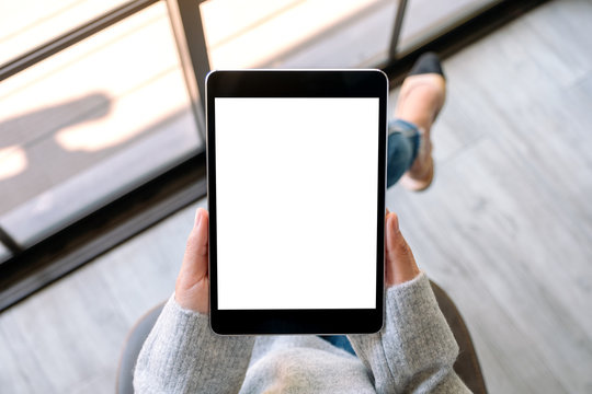 Top view mockup image of a woman holding black tablet pc with blank white screen