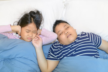  Sister closing ears with hands suffering from loud snore.