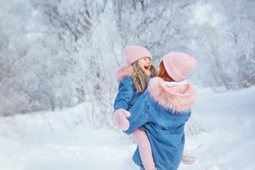 Young woman holds little girl and little girl hugs Young woman in woods in winter