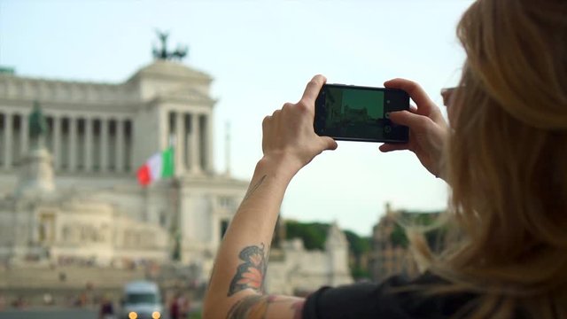Caucasian woman takes photo of historic Rome Building with phone, slow motion