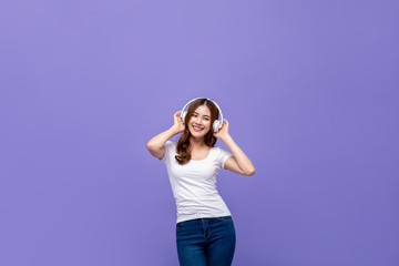 Obraz na płótnie Canvas Pretty Asian woman dancing and listening to music on headphones