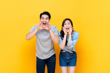 Young lovely asian couple yelling with hands cup around mouths
