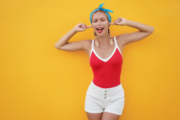 To loud! Young pretty woman closes her ears with fingers refusing to listen to something. Yellow...