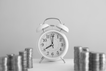 Alarm clock and coin piles arrange into growth chart on white background, finance and business concept