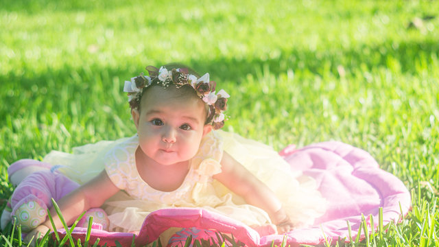 Baby wreath flowers yellow dress in the garden, sitting on the grass looks at camera