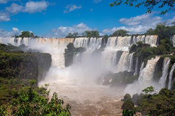 Panoramic view to cascading water falls, brown river and blue sky, Iguazu Falls, Argentina