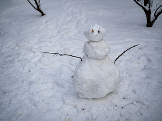 Simple snowman standing alone in the park during cold winter day