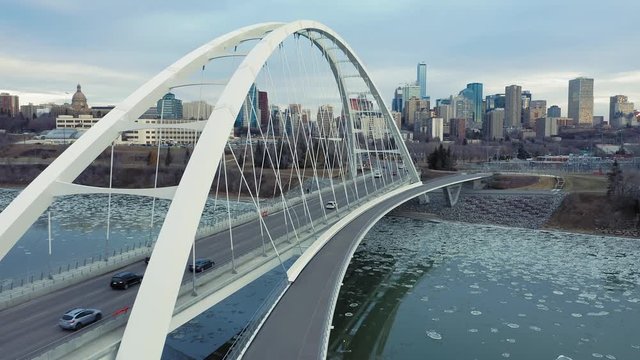 Aerial: Edmonton city skyline & traffic on Walterdale bridge, which crosses the North Saskatchewan River. Ice is flowing along the river. Edmonton, Alberta, Canada. 