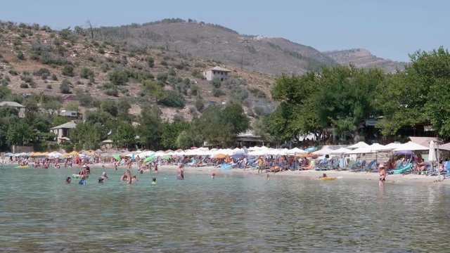 This video shows crowded Alyki Beach in Thasos, Greece. People are sunbathing and enjoying the nice water.