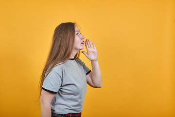 Attractive caucasian young woman over isolated orange wall speaking, keeping hand near mouth, wearing nice shirt with brunette haircut