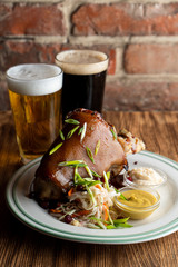 Juicy ham hock with sauerkraut, mustard and horseradish on wooden table
