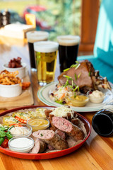 Beer with snacks: sausages, mustard, potato and croutons with other snacks on background