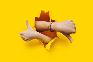 Like and dislike. Thumbs up and down sign of a man's and woman hand. The wrist came out through the...
