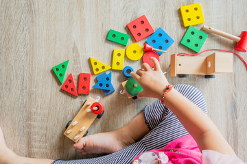 Selective​ focus.​ Body​ part of​ baby​ girl​ playing​ the​ wooden​ block toys.​ On​ wooden​ floor.​ 1-2​ years​ old​ of​ child.​ Learning​ and​ development​ of​ kid​ concept.