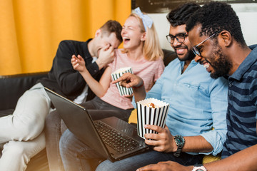 A group of friends using laptop and laughing
