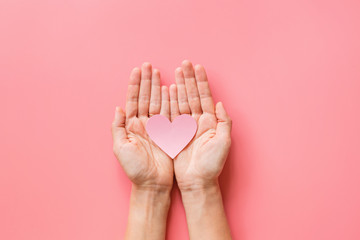 Valentine's day background. Female hands holding pink hearth. Flat lay, top view, mockup, template,...