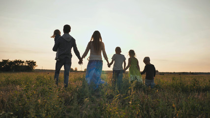 Fototapeta na wymiar A large family walks along the field at sunset.