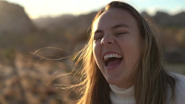 Cute young woman laughing hysterically in an outdoor, rural setting - static close up