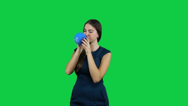 Girl blowing up a balloon in front of a green screen
