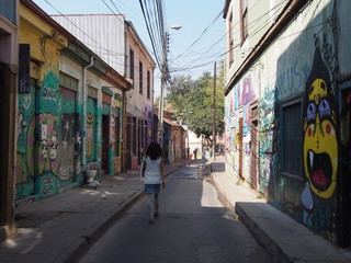 Fototapeta na wymiar A woman walking through the city with beautifully designed walls and streets, Colorful houses and streets of the port city, Valparaiso, Chile