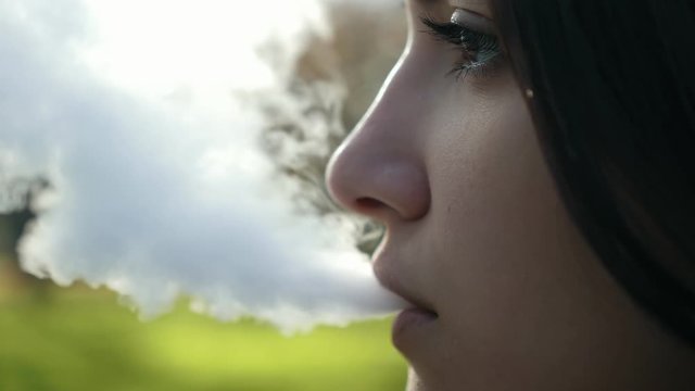 Closeup face of cute caucasian woman vaping e-cigarette outdoors