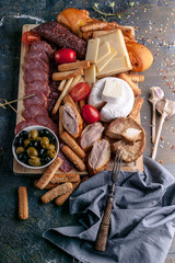 Assorted cheeses, smoked sausages and meat on a cutting board. Mediterranean food. Top view. Vertical shot