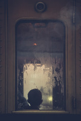 Vintage train window with a silhouette of a child seen behind a wet window