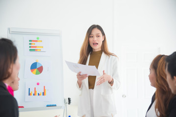 Beautiful asian businesswoman present business profit to her business colleague in office.