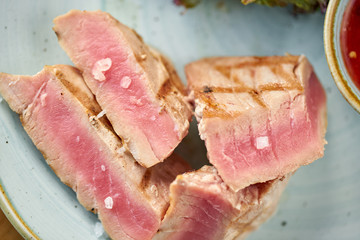 Closeup Medium rare tuna with lettuce and hot sauce. Restaurant menu