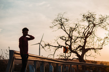 Indian male model standing in front of the tree and windmill during the sunset at Wankaner, Gujarat, India