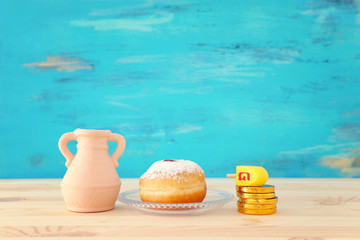 religion image of jewish holiday Hanukkah with spinning top and doughnut over wooden table and blue background