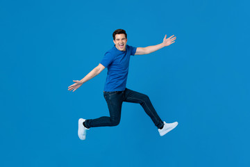 Energetic handsome man jumping and smiling with outstretched hands