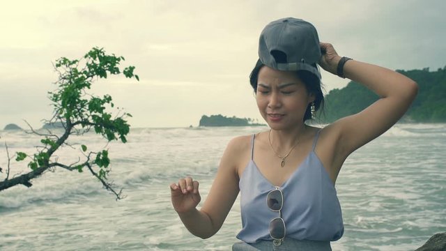 Young Thai Woman wearing cap at island tropical beach. Slow motion