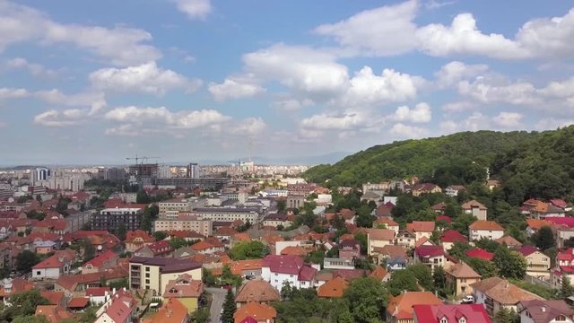 Aerial view of Brasov city, medieval town situated in Transylvania, Romania. Old architecture surrounded with big Carpathian mountains covered with dense green forest.