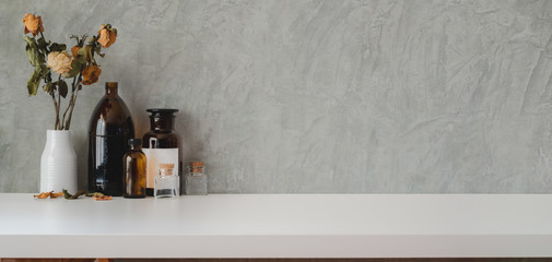 Close-up view of vintage workplace with vase decorations and copy space on marble table and grey wall © bongkarn
