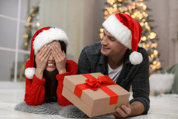 Fototapeta na wymiar Man presenting Christmas gift to his girlfriend at home
