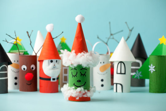 Paper toy Santa, Snowman, Grinch for Xmas party. Easy crafts for kids on blue background, copy space, die creative idea from toilet tube roll, recycle reuse eco concept