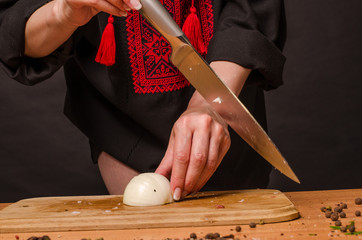 Girl's hand with a knife cutting onions on wooden Board
