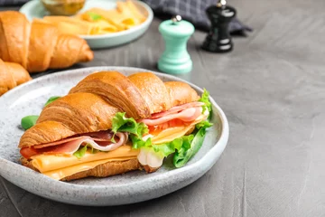 Foto op Canvas Tasty croissant sandwich with ham and cheese on grey table © New Africa
