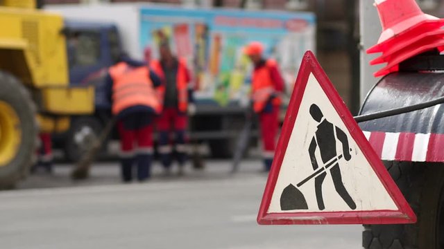 Roadworks signs on a street. Roadworks sign on a road. Road sign repair work and detour arrow. Repair work on the road. Workers laid new asphalt.