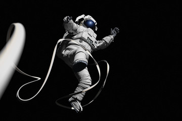 astronaut with safety tether performing a spacewalk, isolated on black background 