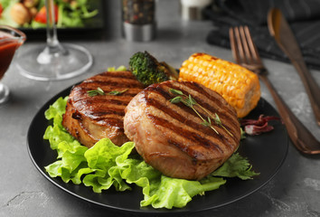 Delicious beef medallions served on grey table, closeup