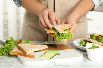 Woman making tasty sandwich at white marble table, closeup