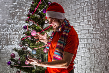 Angry and aggressive Santa is holding a mobile phone while standing near the Christmas tree.