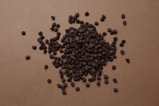 Pile of delicious chocolate chips on brown background, top view