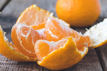 Naklejka na ściany i meble Peeled mandarin without peel and slices of ripe mandarin are on the table.