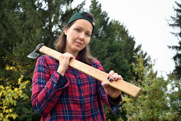 Female lumberjack holding a huge axe on her shoulder