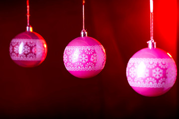 Traditional pink christmas balls on a black background with red backlight.