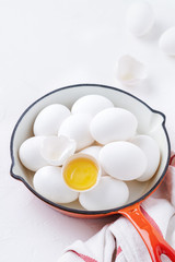White raw chicken eggs in red pan on light background. Top view.
